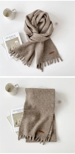 Detail of mocha brown knit scarf with fringe trim and premium leather brand label