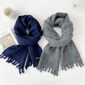 Navy and grey thick knitted scarves with tassels and leather labels on white background