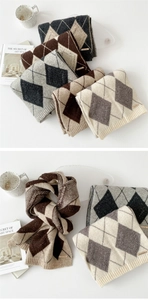 Detail of argyle knit scarf with textured diamond patterns and brand logo label
