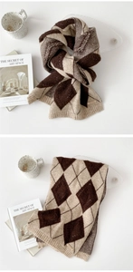 Detail of knitted scarf with argyle pattern in brown and beige colors with leather label