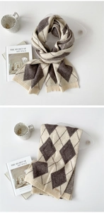 Detail view of thick argyle knit scarf in beige and brown with ribbed edges and small tag