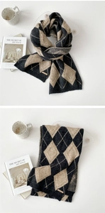 Detailed close-up of knitted argyle pattern scarf with premium leather brand label