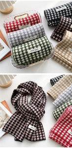 Detailed view of knitted houndstooth scarf texture with woven label on soft white background