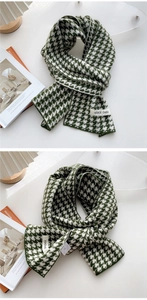 Detail of forest green and cream houndstooth knit scarf with woven brand label