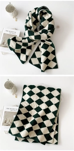 Detail view of thick knitted scarf with dark green and cream diamond pattern textures