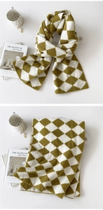 Macro detail of the thick argyle knit pattern in olive green and cream yarn