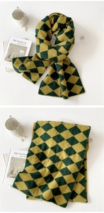 Close-up of green and yellow diamond pattern knitted scarf with soft wool texture