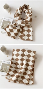 Detail of soft brown and white argyle knit scarf with warm chunky texture and cozy drape