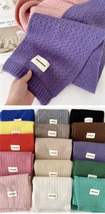 Detail view of colorful hollow knit scarf texture and brand tag on soft warm fabric