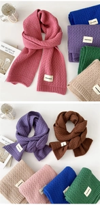 Detail view of colorful rib-knit scarves with woven labels in a stylish lifestyle setup