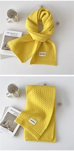 Detail of soft yellow knitted scarf texture and white woven label with black text