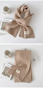 Detail of warm beige honeycomb knit scarf with soft texture and minimalist brand label