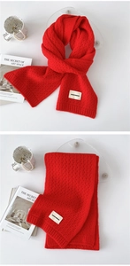 Close-up of red knit scarf with honeycomb texture and branded woven label detail