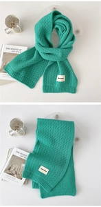 Detail of emerald green hollow knit scarf showing delicate texture and woven logo label