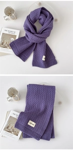 Detail of purple knit scarf with pointelle texture and fabric brand tag on white surface