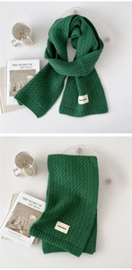 Detail of dark green knitted scarf with thick weave texture and brand woven label