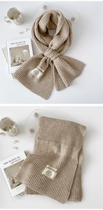 Close-up of oatmeal chunky ribbed knit scarf with cross-slot design and material label