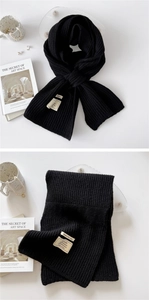 Close-up of black knit scarf showing Warm for you fabric label and material composition