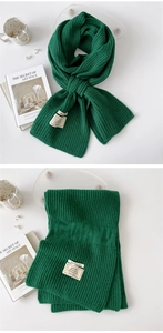 Detailed view of dark green ribbed knit scarf with material composition label