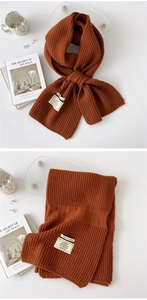 Close-up of caramel knit scarf showing chunky vertical rib texture and fabric label