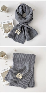 Detail view of dark grey ribbed knit scarf showing fabric texture and care label