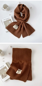 Detail of caramel knit scarf with ribbed texture and material label on white background