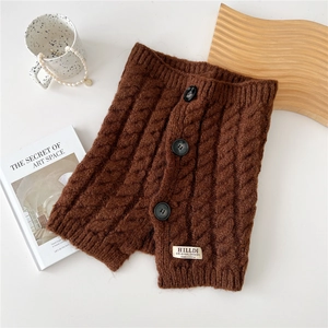 Detail of dark brown cable knit neck warmer featuring elegant buttons and brand label