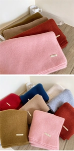 Detailed close-up of colorful thick knit wool scarves with golden metal brand labels
