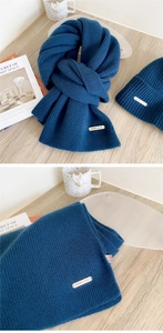 Detail of dark blue ribbed wool scarf with 100% wool label and metal logo accent