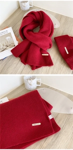 Detail of red 100% wool knitted scarf and hat set with chunky texture for winter warmth