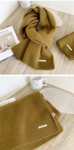 Detail of khaki knitted scarf and beanie set with fine ribbed texture and metal label