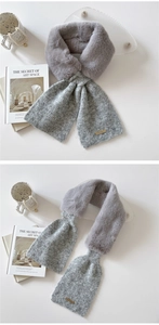 Detail of grey faux fur scarf with knit hem and elegant metal brand plate on white desk