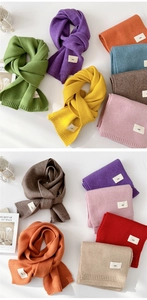 Close-up of colorful knit scarves with ribbed edges and minimalist 'emo' brand labels
