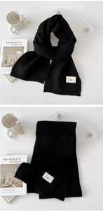 Close-up of black knitted scarf with minimalist white logo tag on a lifestyle background