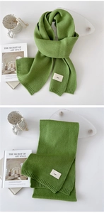 Detail of grass green knitted scarf with ribbed edge and emo fabric label on white background