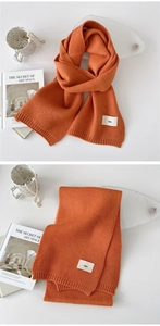Detail of vibrant orange knitted scarf showing soft texture and Emo logo label