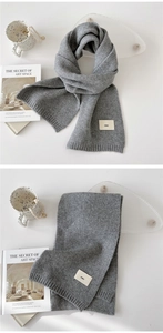 Detailed macro view of gray knitted scarf showing ribbed edge and decorative emo label