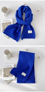 Close-up of royal blue knitted scarf featuring a minimalist emo logo tag and ribbed edges