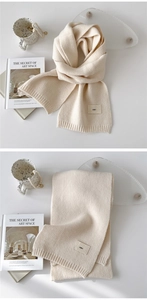 Detail of soft cream knitted scarf featuring ribbed edges and minimalist emo fabric patch