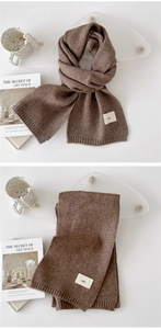 Detail of dark brown knitted scarf with soft texture and minimalist woven label