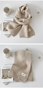 Detail view of beige knitted scarf with minimalist emo label and ribbed texture