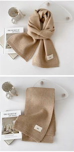 Close-up of camel knit scarf showing ribbed edges and a minimalist emo fabric label