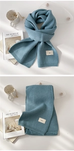 Detail of blue chunky knit scarf with minimalist emo label on a soft textured fabric