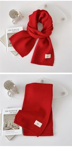 Detail of red knit scarf with minimalist emo label and cozy thick wool texture
