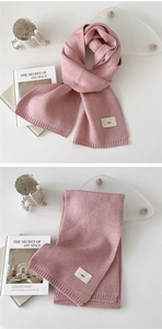 Detail of pink knitted scarf with decorative 'emo' woven label on soft wool-like fabric