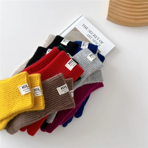 Colorful knit fingerless gloves and socks display with stylish HIL ORIGINAL woven labels