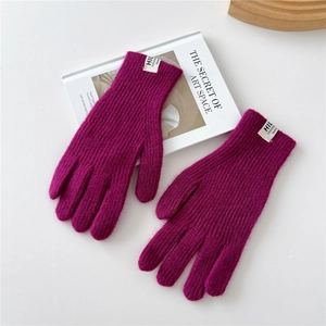 Close-up of magenta ribbed knit gloves with white logo label on artistic background