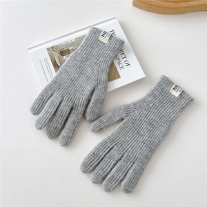Detail of gray knitted gloves with ribbed texture and minimalist brand label on book