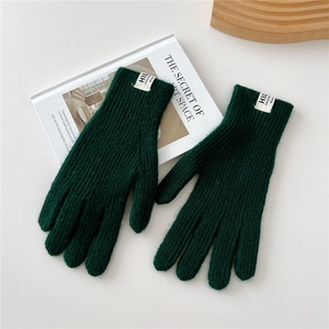 Close-up of deep green ribbed knit gloves with white logo tag on white background