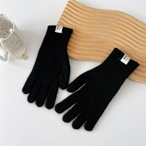 Close-up of black knit gloves with soft texture and white branded woven label on wrist